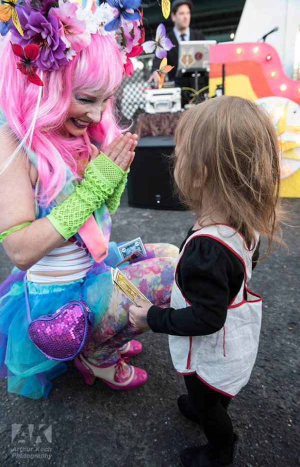 Woman leaning down to clap with a child at Mystic Midwayville Festival