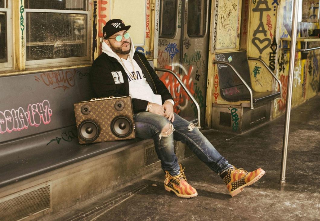 BIPOC man sitting on subway train bench with black baseball cap and reflective sunglasses